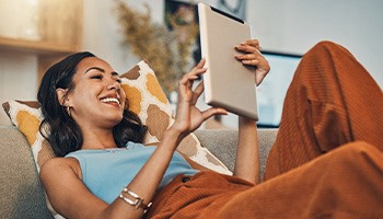 Smiling woman with tablet relaxing on couch