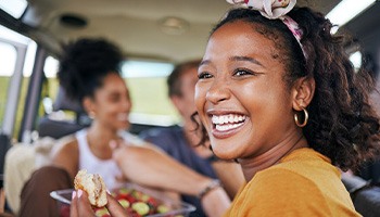 Woman smiling while eating meal with friends in car