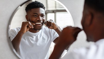 Man smiling while flossing his teeth
