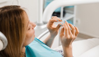 Patient holding clear aligner in treatment chair