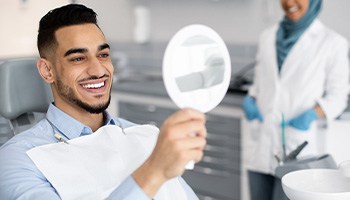 Man smiling at reflection in mirror in treatment chair