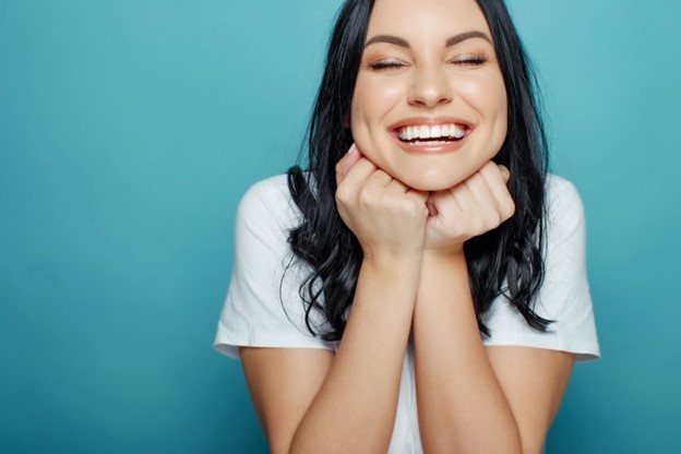 person holding Invisalign aligner and smiling